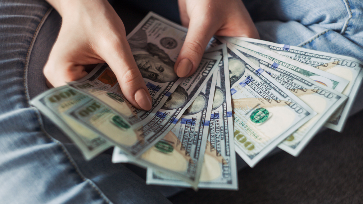 Person counting 100 dollar bills in hand