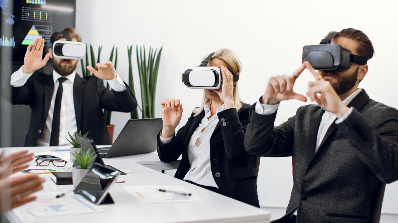 Three coworkers sitting at a table wearing VR goggles