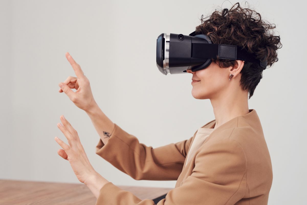Woman wearing virtual reality goggles moving her hands.