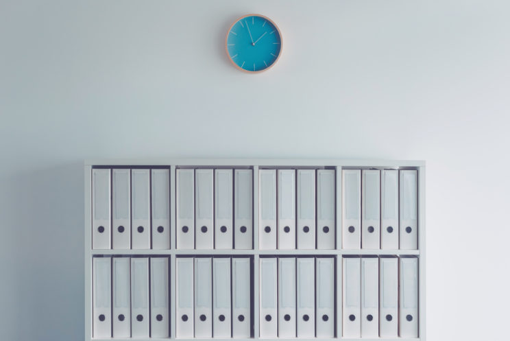 Document ring binders in business office with clock on the wall as conceptual image for fiscal year bookkeeping and tax accounting with copy space included