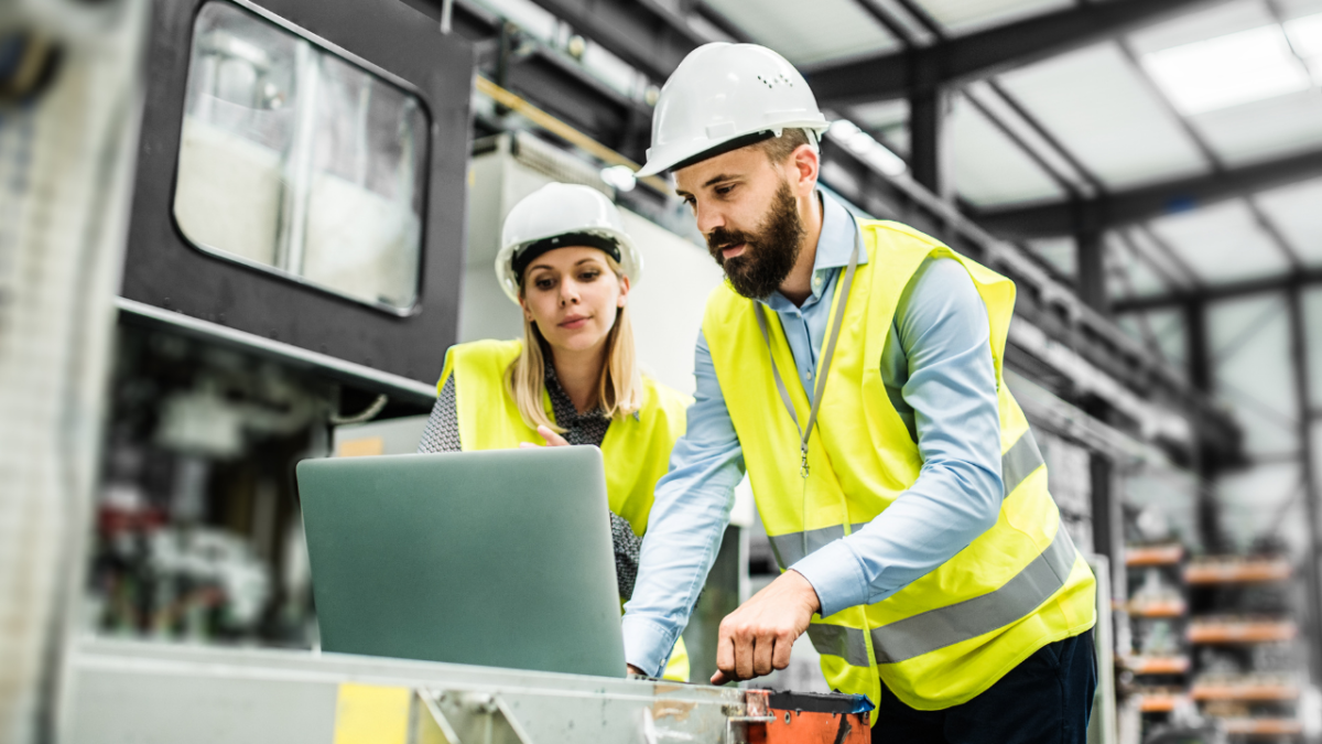 2 factory workers looking at a laptop